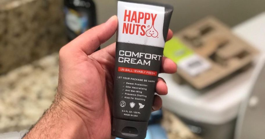 man holding Happy Nuts Comfort Cream 3.4oz Bottle in bathroom
