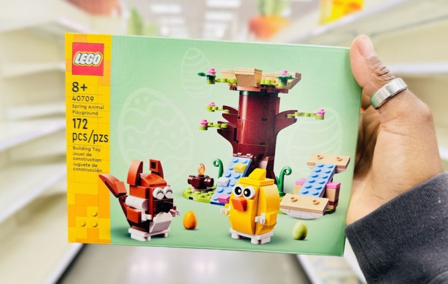 a womans hand holding a LEGO spring animal playground building kit