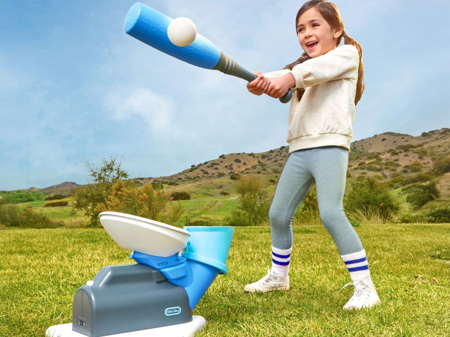 Girl hitting a ball being pitched from the Little Tikes 2-in-1 Pop 'n Pitch Trainer