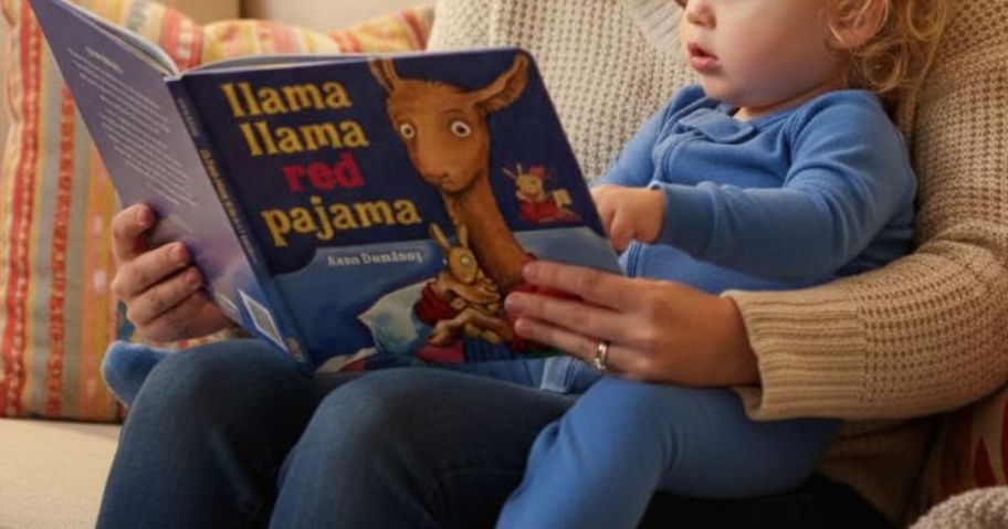 Baby sitting on a mom's lap reading a llama llama book