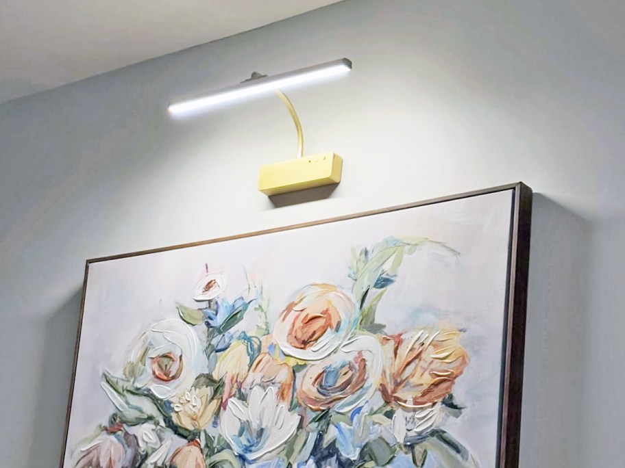 gold light on wall illuminating floral artwork