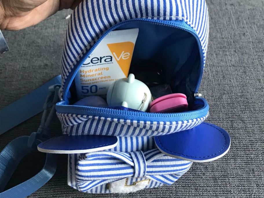 a white and blue striped crossbody bag with the letter "C" on it
