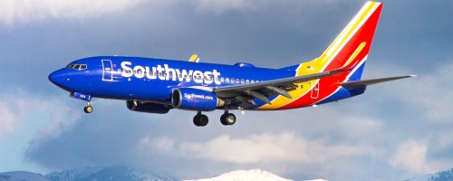 Southwest Airlines plane landing with snowy mountains in background