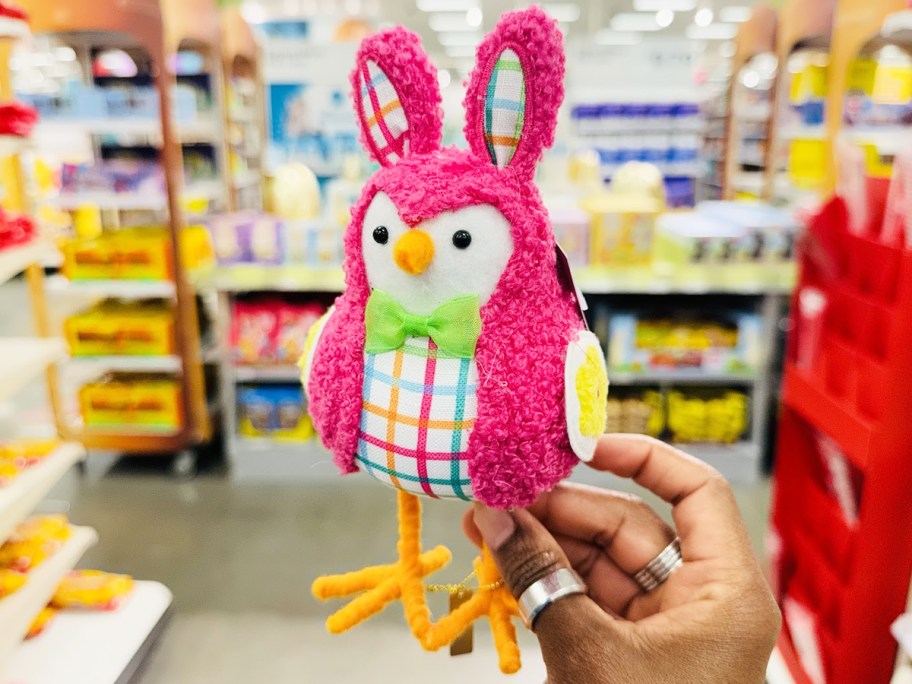 hand holding up a pink felt bird dressed as a pink bunny