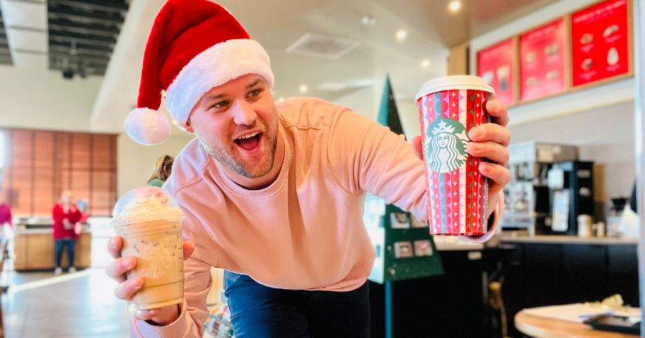 Man wearing a Santa Hat Holding two holiday drinks