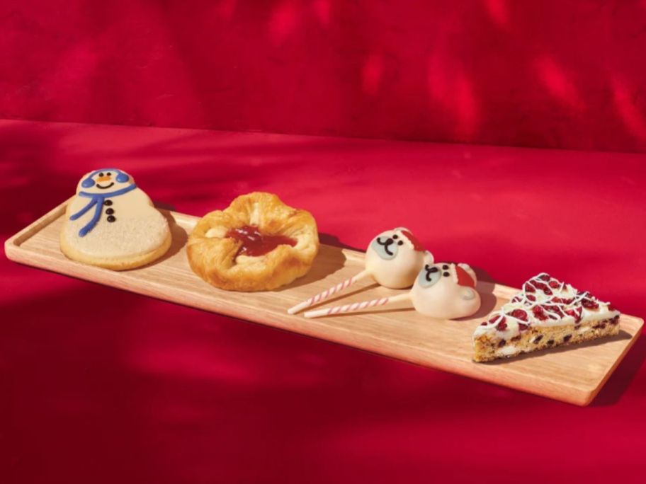 A woden tray with Starbucks Snowman Latte, Sugar Plum Danish, Polar Bear Cake Pops and Cranberry Bliss Bar