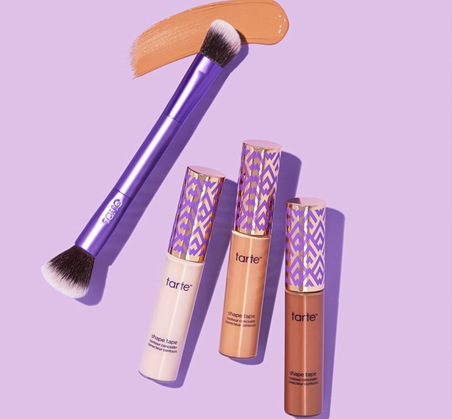 three tubes of Tarte Shape Tape Concealer and purple double ended brush