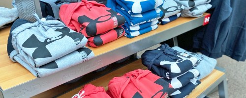 display table full of folded under armour hoodies in various colors