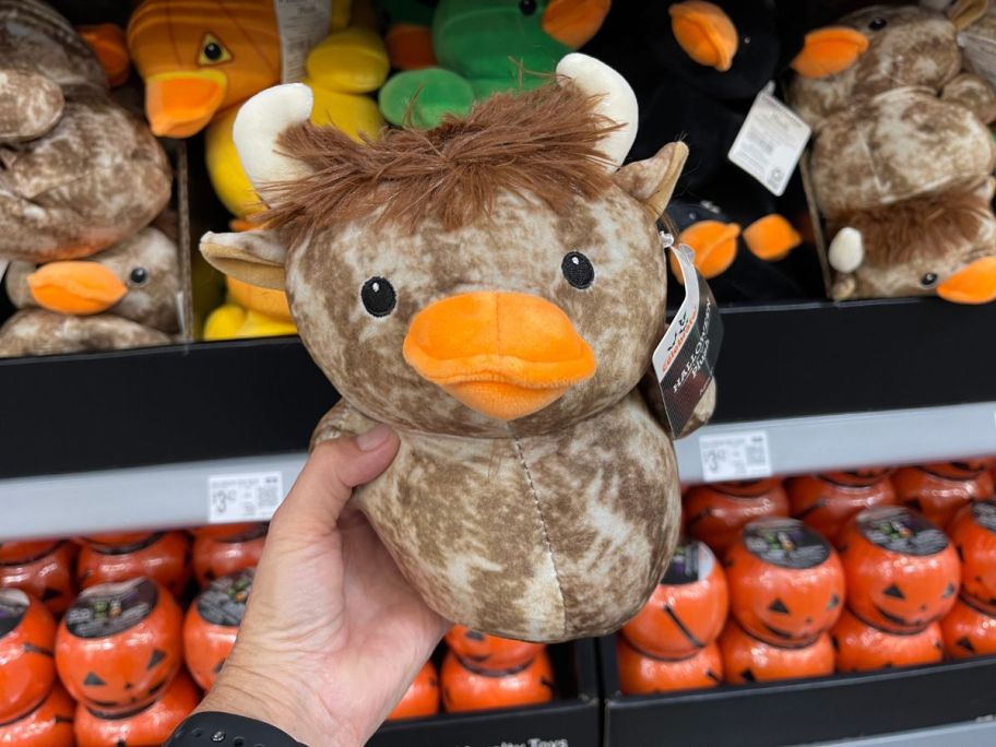 A person holding a plush duck that looks like a cow