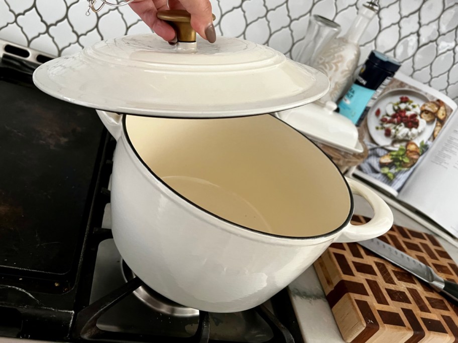 hand lifting lid on white dutch oven