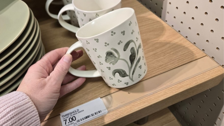 womans hand holding a hand painted coffee mug