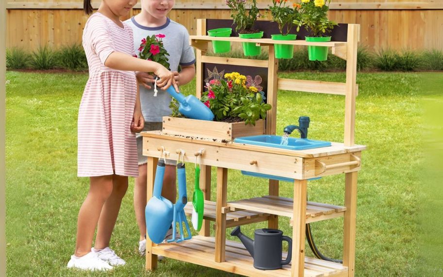 2 kids playing at a mud kitchen outdoors