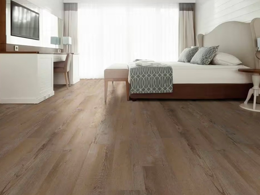 brown wood flooring in bedroom with bed and dresser 