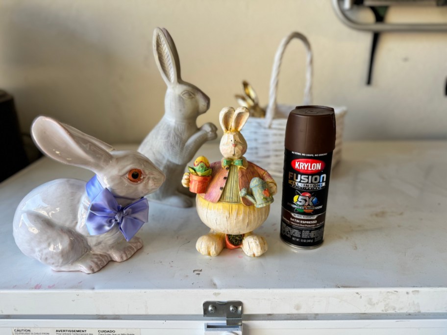 ceramic and wood easter bunnies next to a can of spray paint 