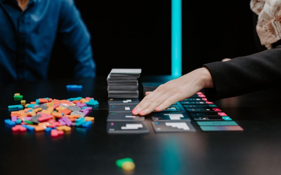 two people playing a tile game on a black table