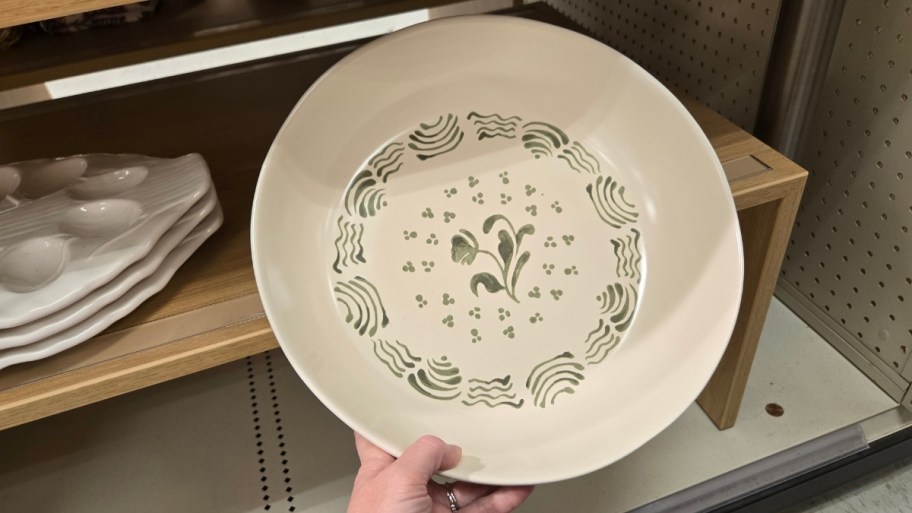 womans hand holding a hand painted rimmed plate