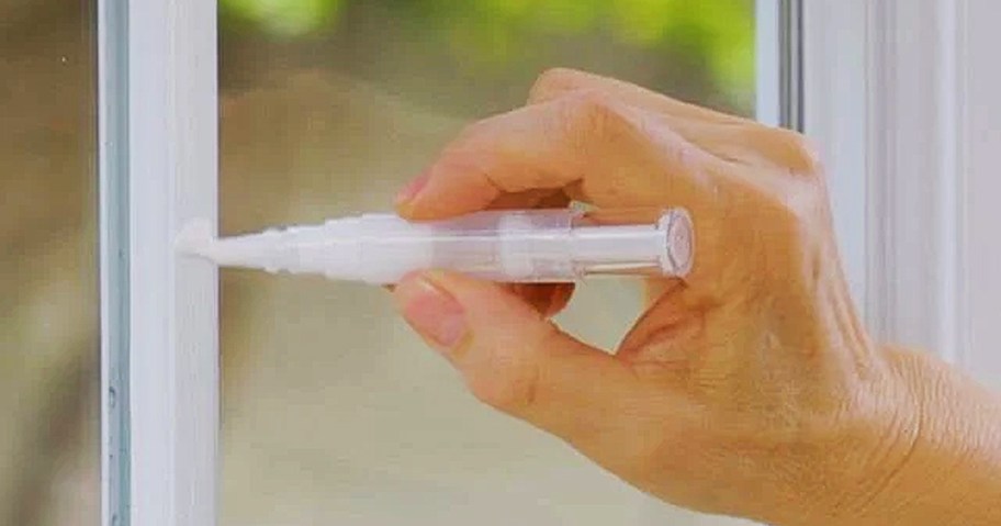 person using paint touch up pen on window frame