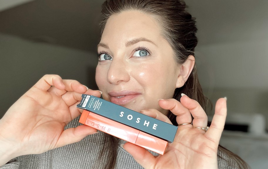woman holding packaging and tube of soshe mascara