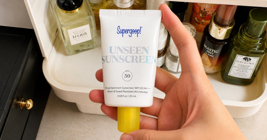 hand holding a Supergoop! Sunscreen tube