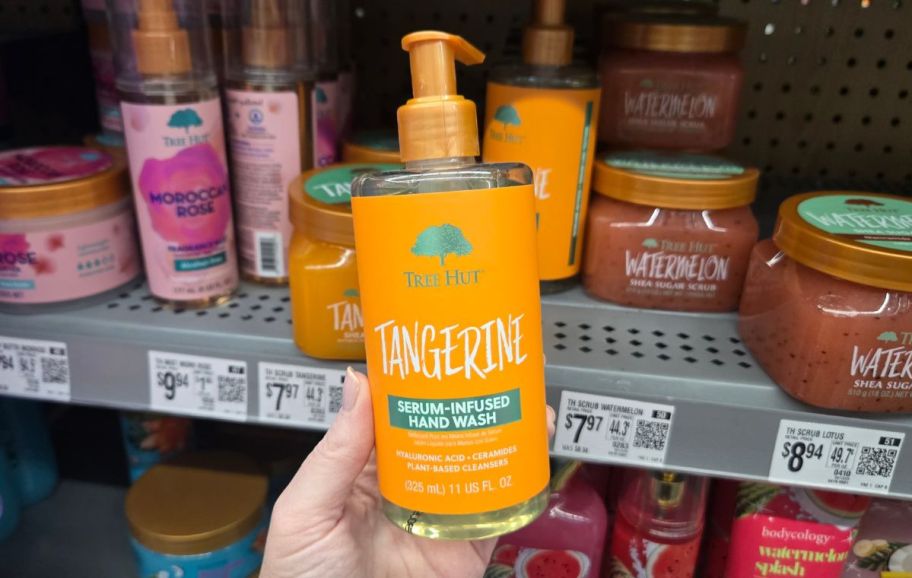 a womans hand holding a bottle of tangerine hand wash