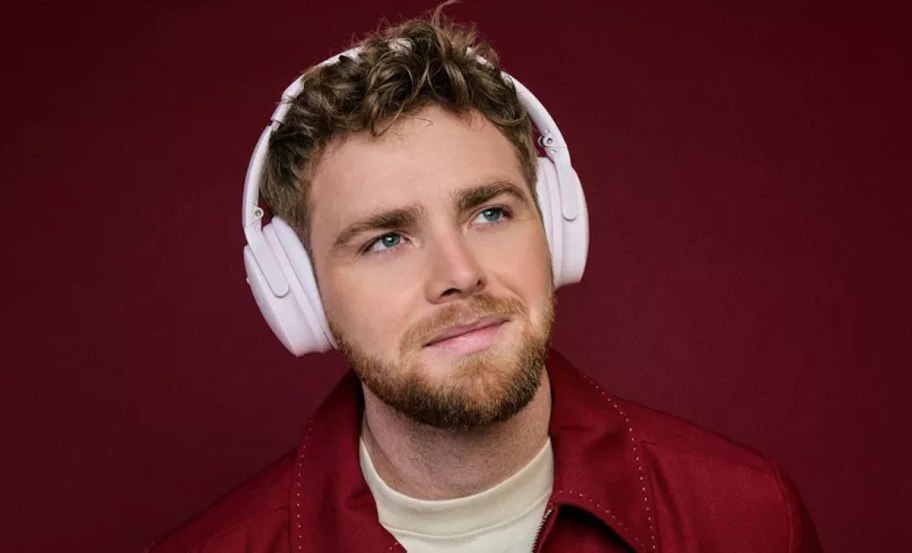 man wearing pink bose headphones with dark red background