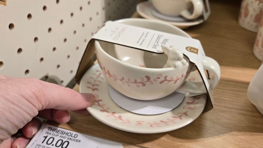 womans hand holding a hand painted tea cup and saucer set