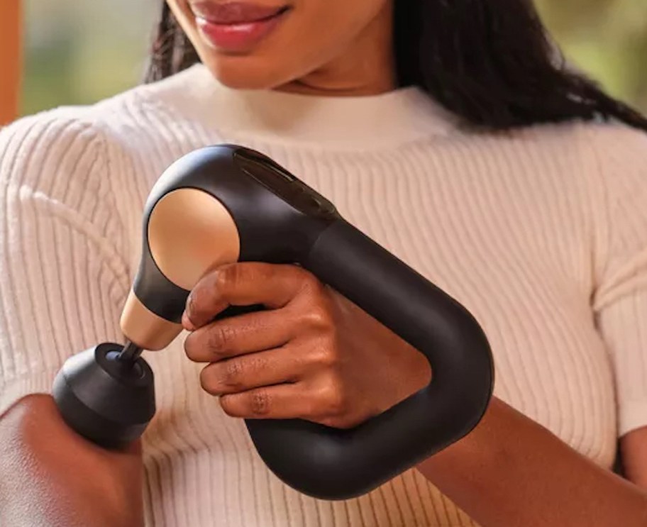 woman holding theragun massage gun on arm