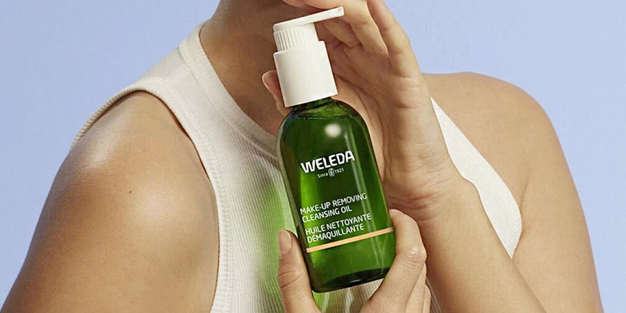 woman holding weleda makeup removing oil bottle