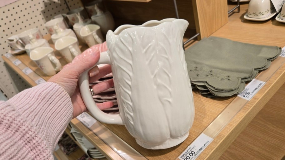 womans hand holding a white radicchio pitcher 