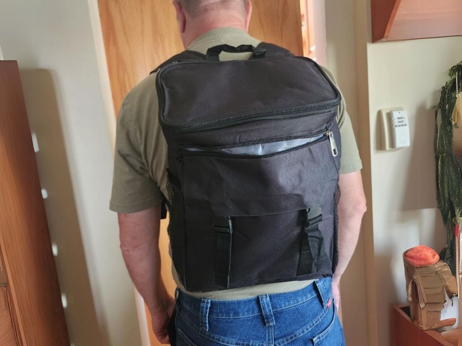 man facing door with 30-Can Cooler Backpack in Black on his back