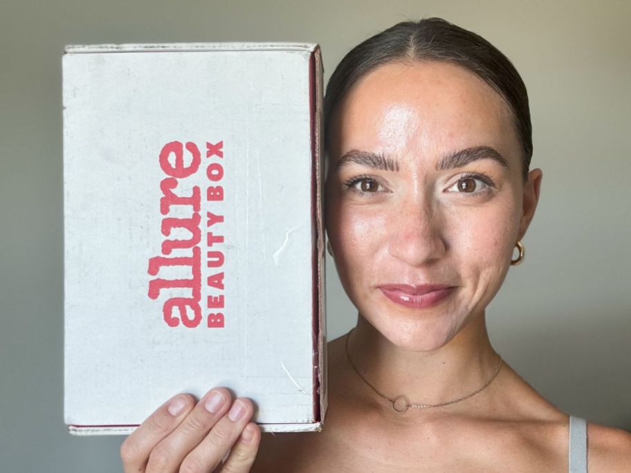 Woman holding an Allure Beauty Box next to her face