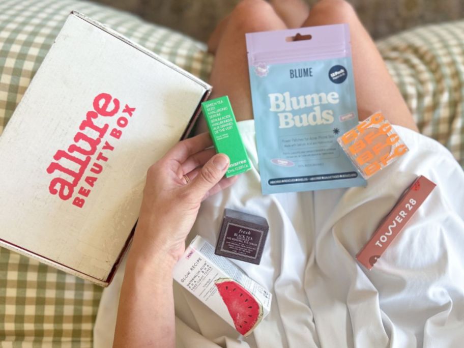 Woman's lap with products from the August 2025 Allure beauty box