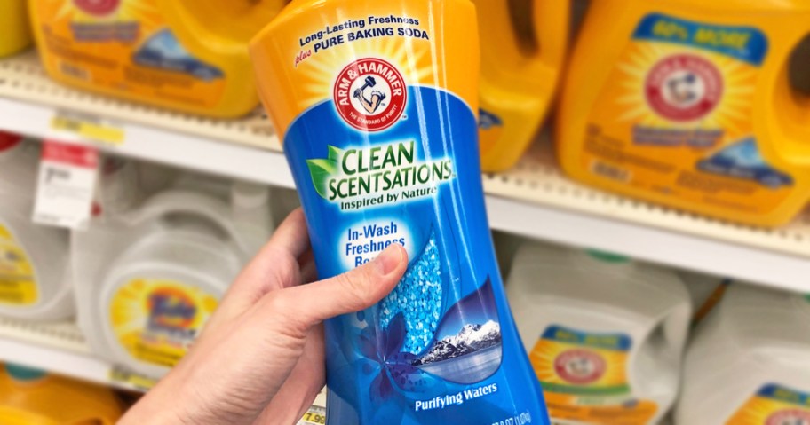 hand holding a yellow and blue bottle of Arm & Hammer Clean Scensations Scent Booster in store