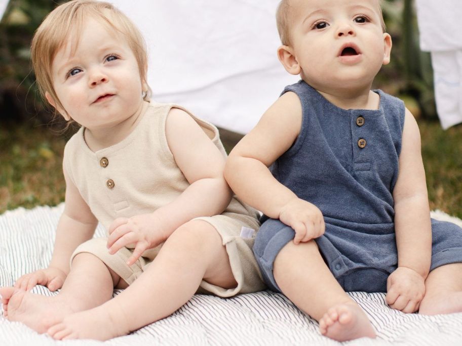 Two babies wearing Burts bees baby cotton onesie while sitting on the floor 