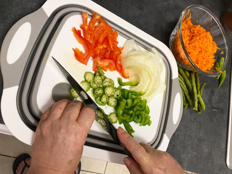 person chopping vegetables on white and grey cutting board