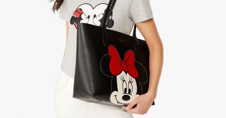A woman carrying a large tote with a Minnie Mouse face on it 
