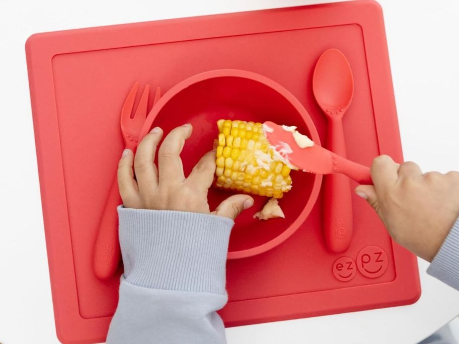 little hands buttering corn in an EZPZ The Happy Bowl