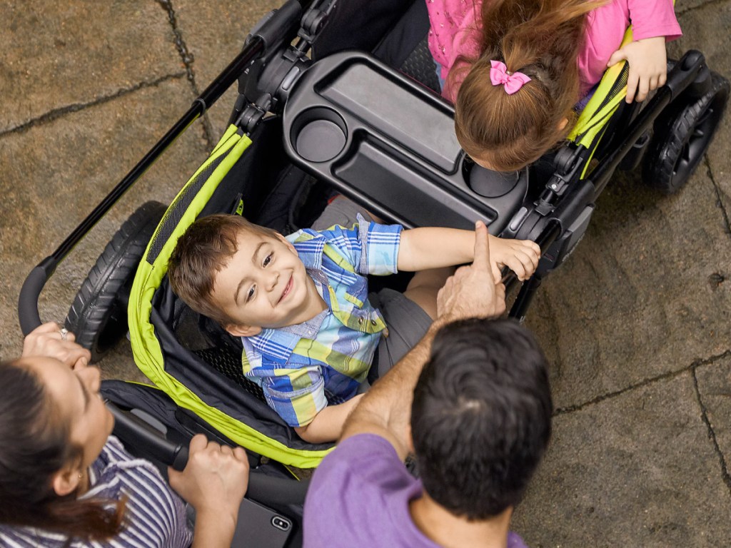 Children looking at the camera inside a dual -seat stroller