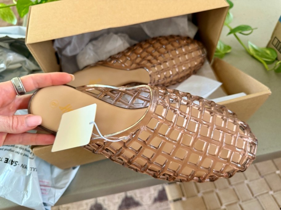 a womans hand holding a jellie mule