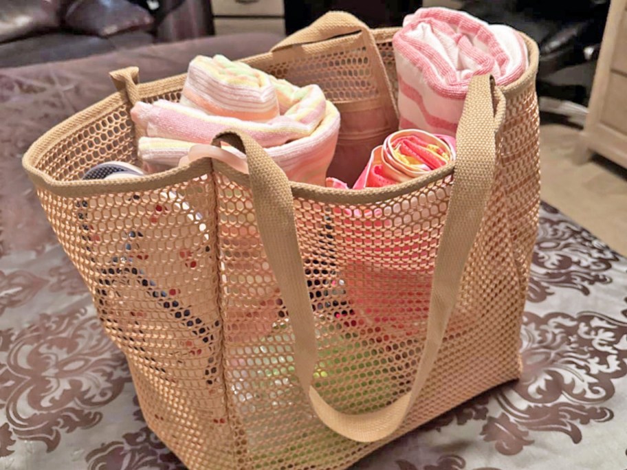 rolled up towels and flip flops inside a tan mesh beach bag