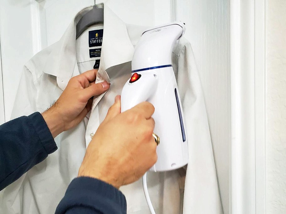 woman using a clothes steamer on a white shirt