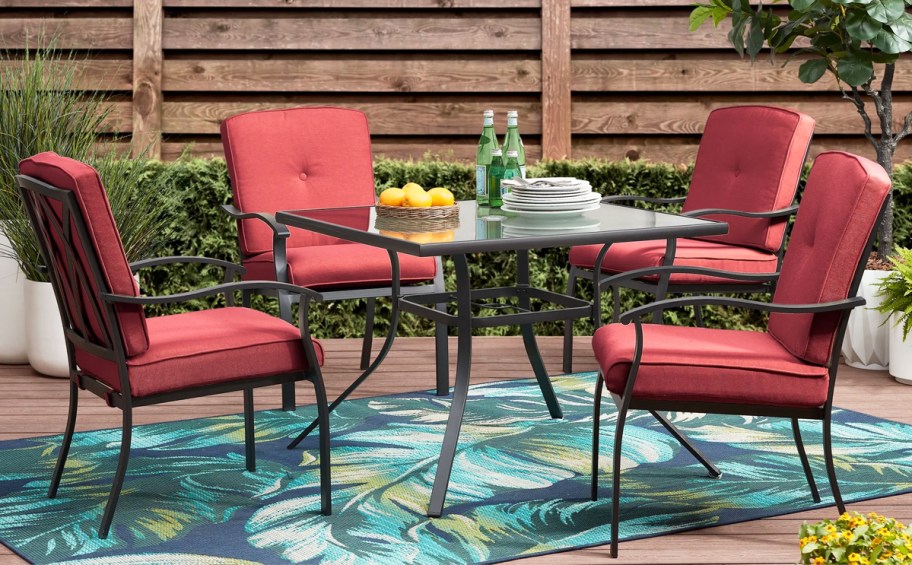 patio set with glass table and 4 chairs with red cushions