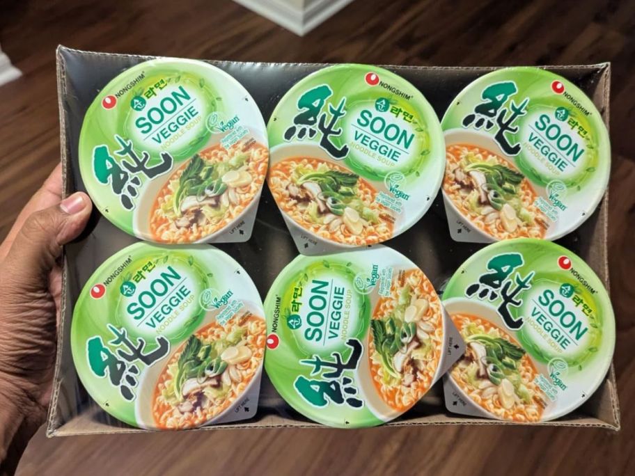A person holding Nongshim Soon Vegan Instant Ramen Noodle Soup Cups 6-Pack