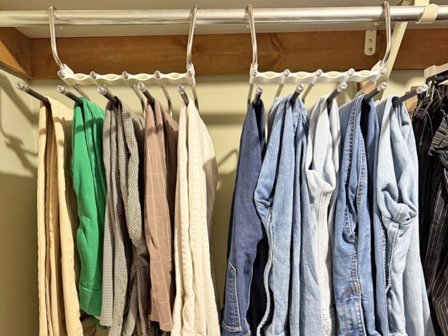 multiple pairs of pants hanging on pants hangers in closet