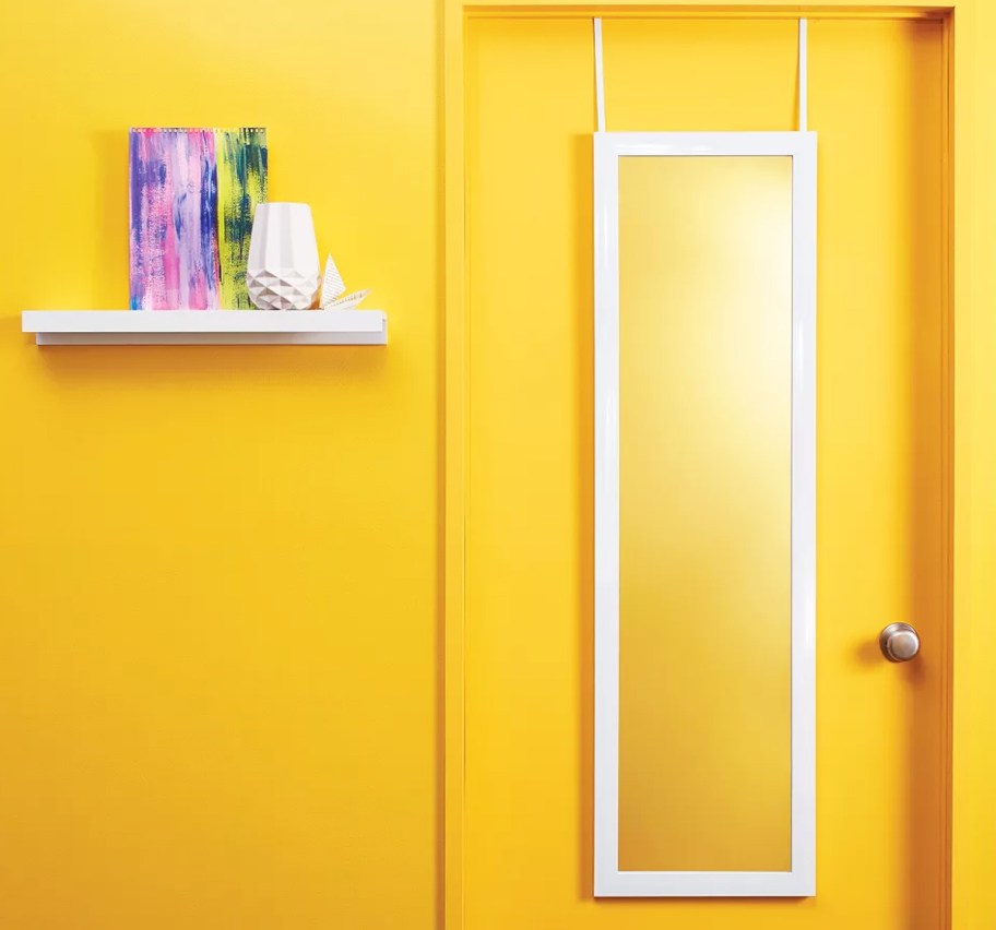 white framed wall mirror hanging on a yellow door