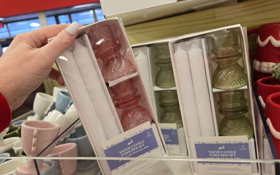 Hand holding taper candle and holder at the store