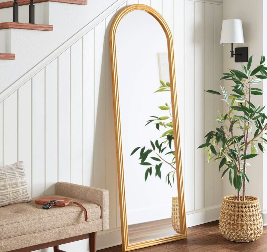 arched floor mirror leaning against wall