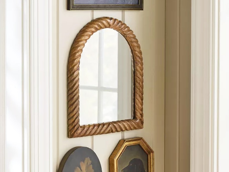 arched wood wall mirror on wall with other wall decor