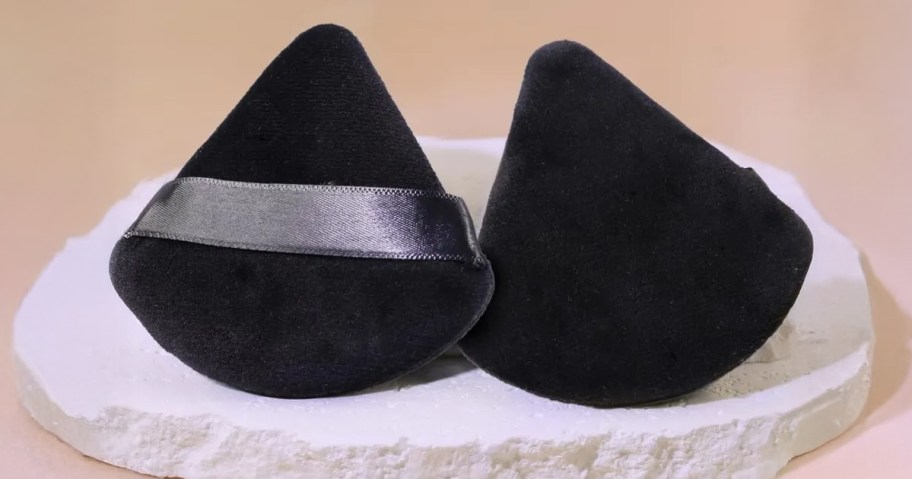 black powder puffs sitting on a white stone