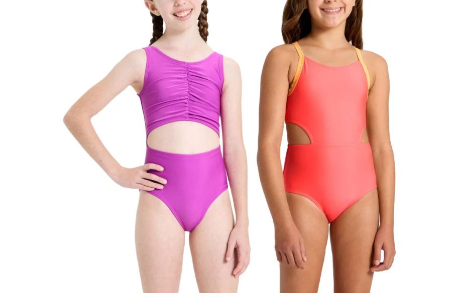 Two girls wearing vibrant swimsuits stand smiling. The left girl wears a purple suit with cut-out detail; the right girl wears a coral suit with yellow straps.